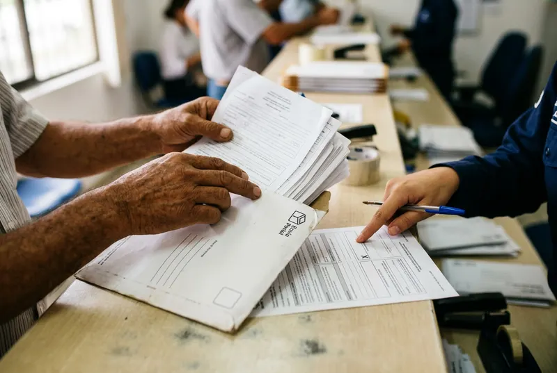 Cliente introduce documentos en un sobre de mensajería internacional con ayuda de la asesora